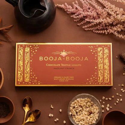 Booja Booja Loglets Hazelnut Crunch chocolate truffle loglets package on a rustic table with decorative elements.