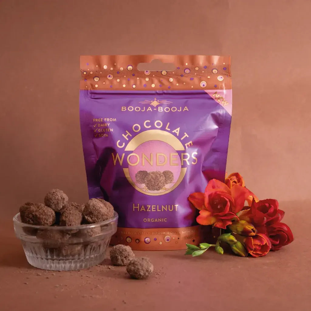 Booja Booja Wonders Hazelnut chocolate delights in a vibrant packaging, surrounded by fresh flowers.