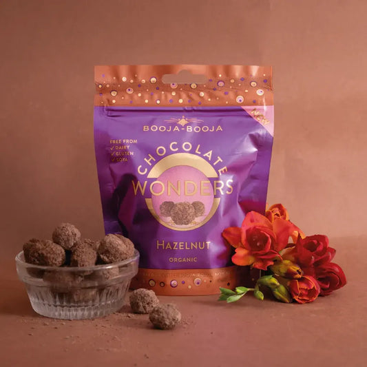 Booja Booja Wonders Hazelnut chocolate delights in a vibrant packaging, surrounded by fresh flowers.