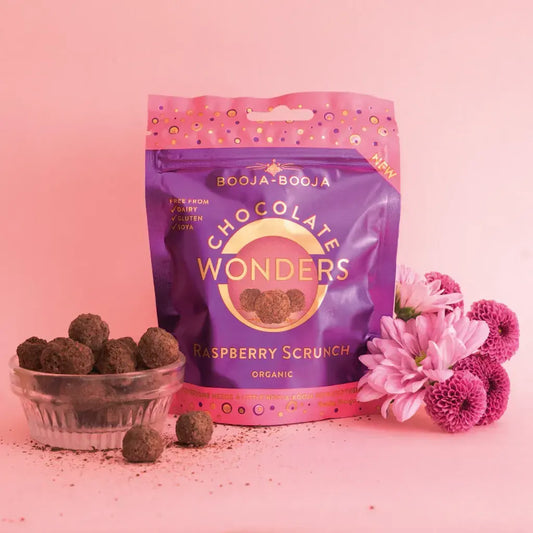 Booja Booja Wonders Raspberry Scrunch chocolate pack with raspberry snack balls and flowers on pink background.