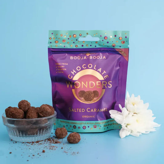 Booja Booja Wonders Salted Caramel packaged with chocolate delights and a bowl of treats on a pastel background.