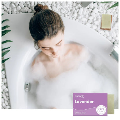 Woman in a bathtub with bubbles and a 'Friendly Soap' lavender bar on a white background.