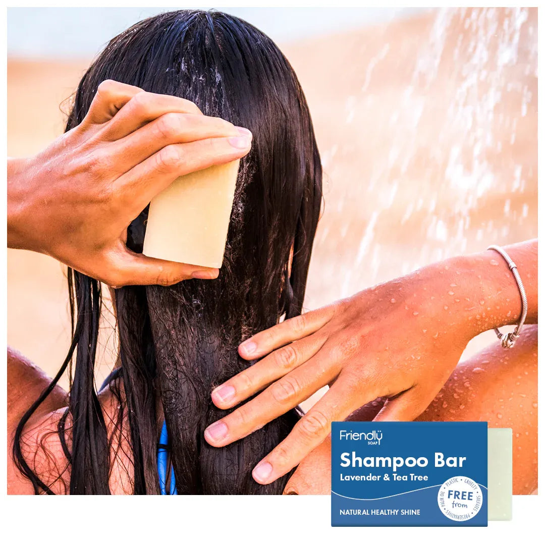 Person using a shampoo bar with water and hair in the background, featuring the Friendly Soap Lavender & Tea Tree Shampoo Bar.