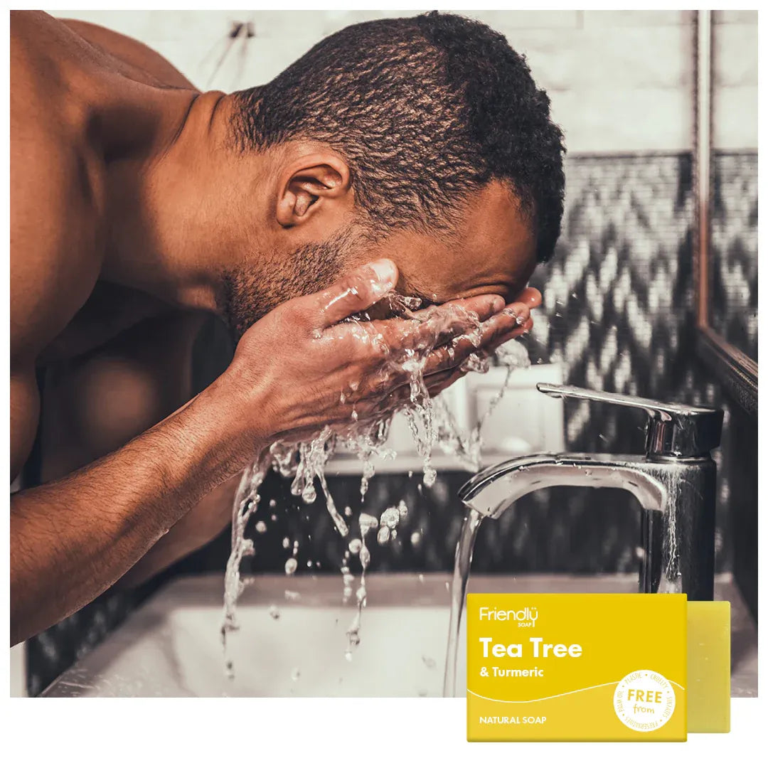 Man washing his face with water from a faucet, with a 'Friendly Soap' bar visible.