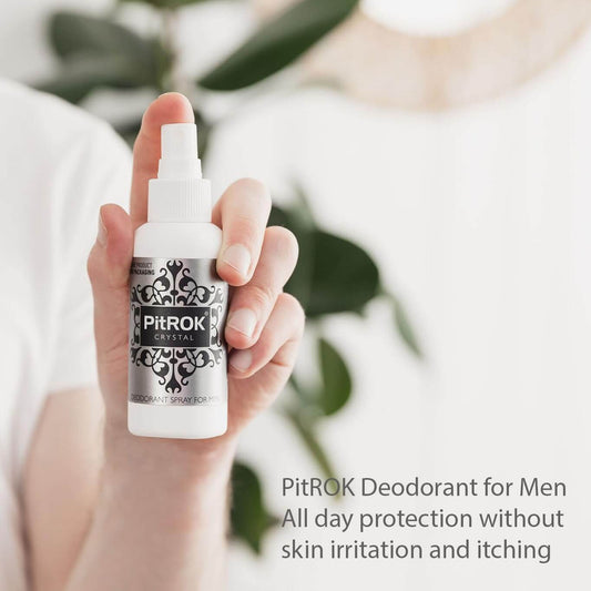 Hand holding a bottle of PitROK 100ml deodorant spray for men with a blurred background.