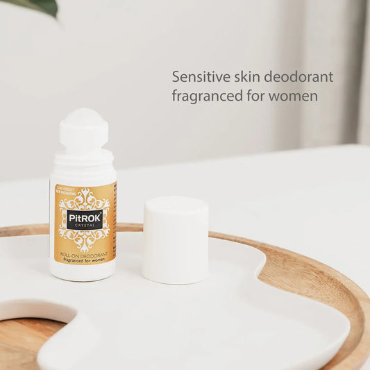 A small white bottle of PitROK Roll-On Deodorant with a gold label sits on a white tray with its cap removed beside it. Text on the image reads 'Sensitive skin deodorant fragranced for women.