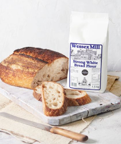 Wessex Mill bread flour bag on table with artisan loaf